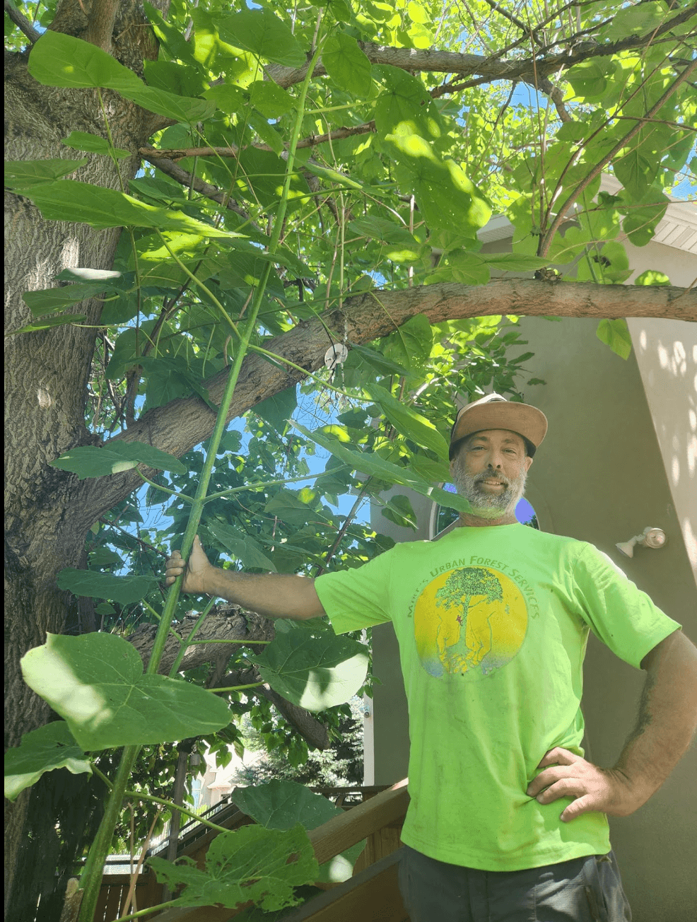Mike, ISA Certified Arborist and owner of Actual Arborists of Utah, beside a young tree in a Salt Lake County yard during summer